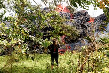 Jolon Clinton, 15, takes photos as lava erupts from a fissure near her home east of the Leilani Estates subdivision during ongoing eruptions of the Kilauea Volcano in Hawaii