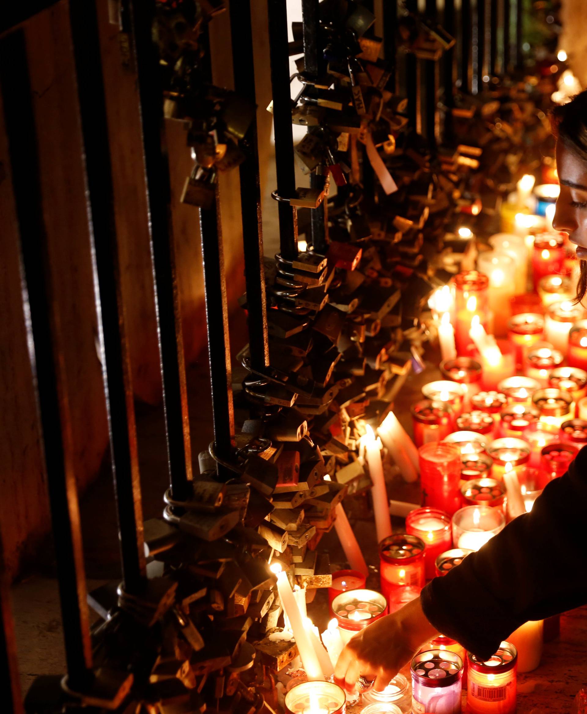 A woman places a candle on the Love monument during a silent candlelight vigil to protest against the assassination of investigative journalist Daphne Caruana Galizia in a car bomb attack, in St Julian's