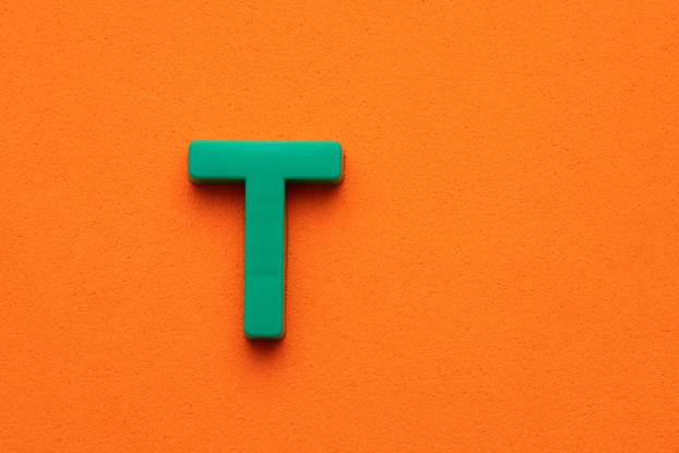 Letter T green plastic uppercase on orange foamy background