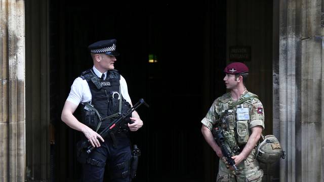 A soldier and police officer stand outside the Houses of Parliament in London