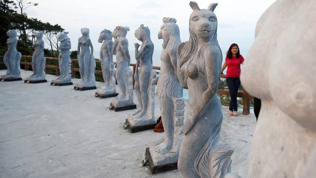 A woman stands near godlike sculptures with animal heads and human genitalia at Hon Dau resort in Hai Phong city, east of Hanoi