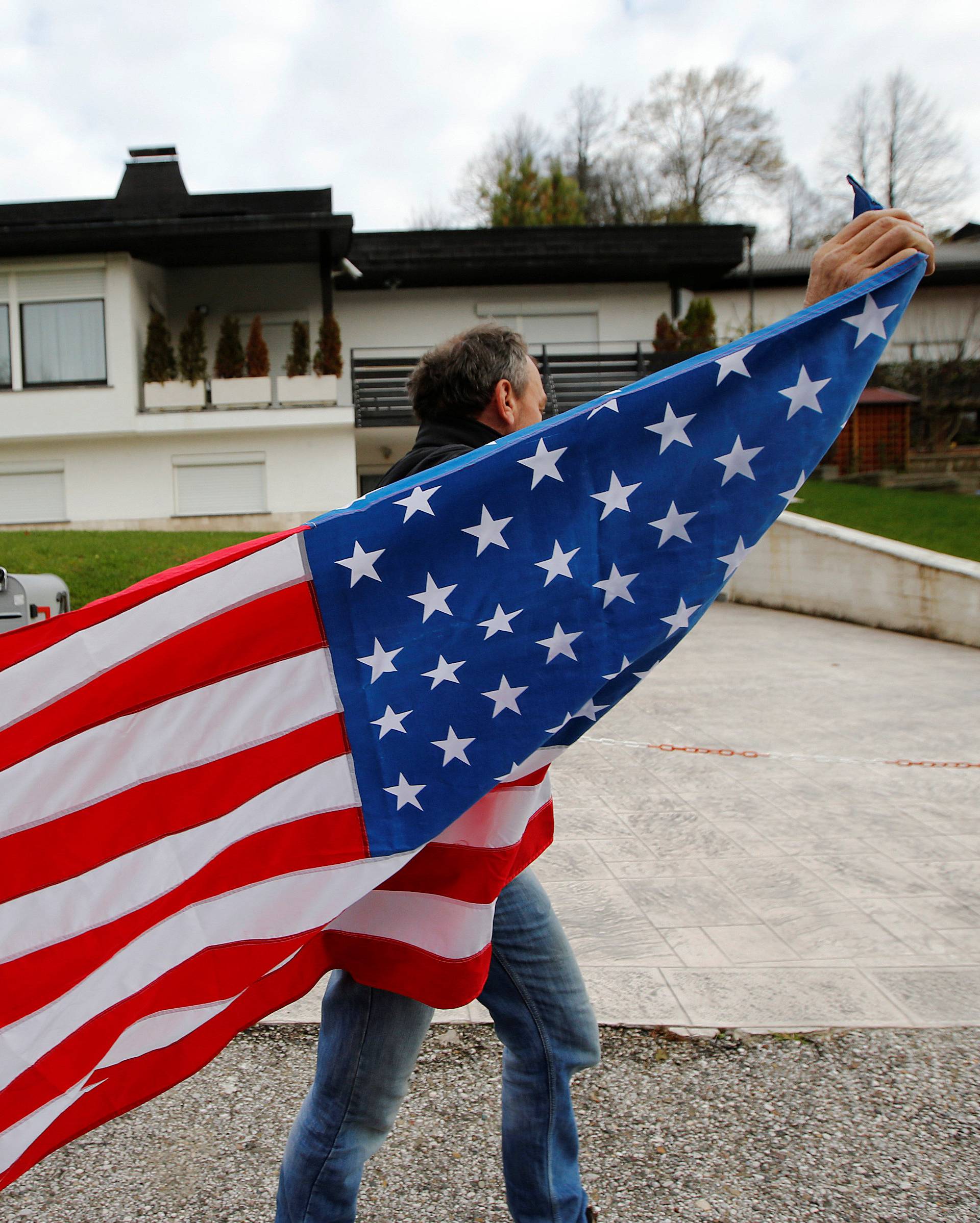 A man carrying the U.S. flag is seen in front of Melania Trump parents' house during the U.S. presidential election in Melania Trump's hometown of Sevnica