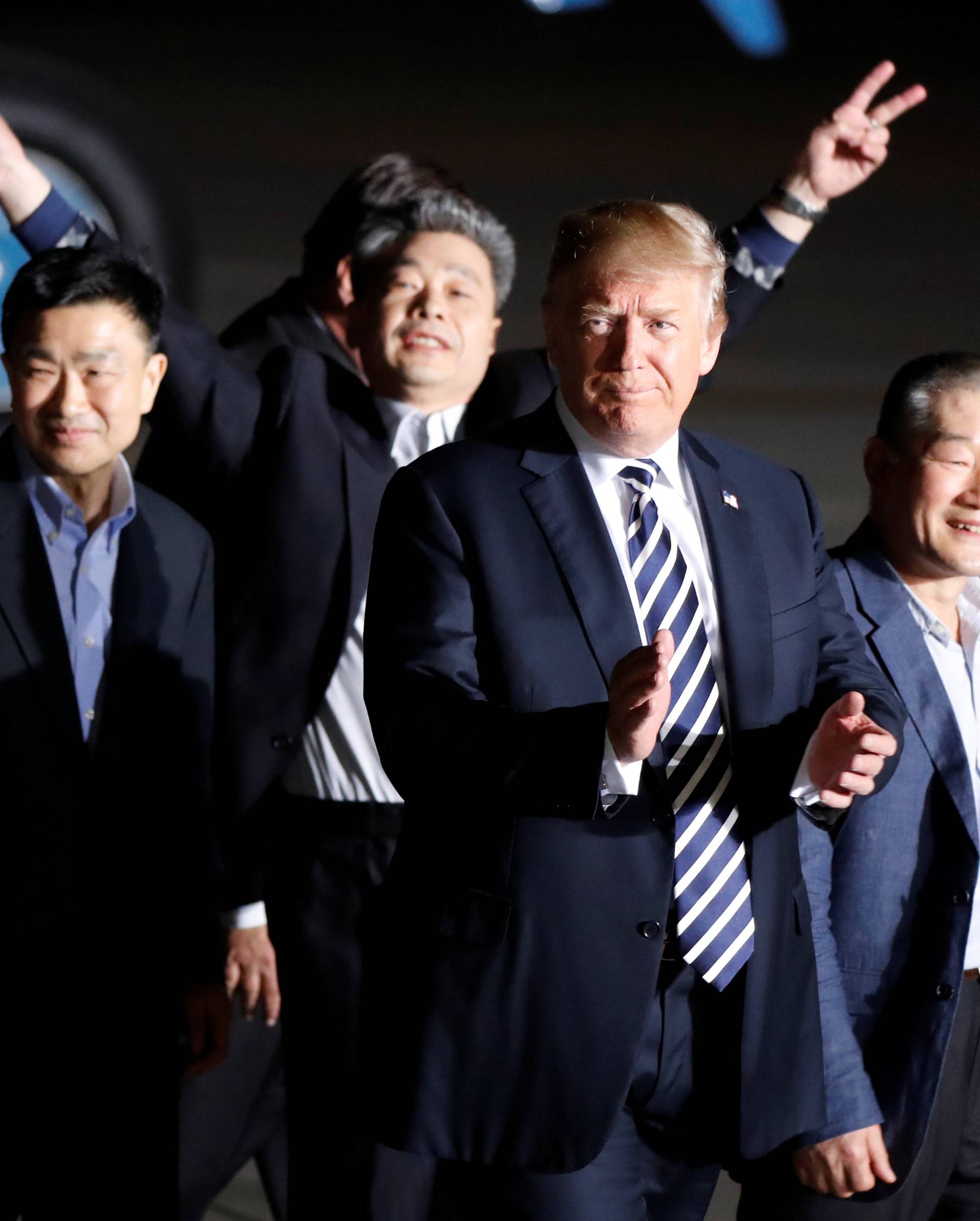 The three Americans formerly held hostage in North Korea gesture next to U.S.President Donald Trump, upon their arrival at Joint Base Andrews