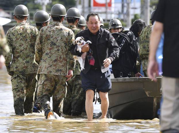 A local resident carrying his pet dog evacuates from an area flooded by the Abukuma river following Typhoon Hagibis in Motomiya