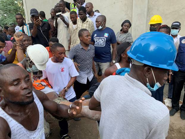 Men carry a worker who was rescued at the site of a collapsed 21-story building in Ikoyi, Lagos