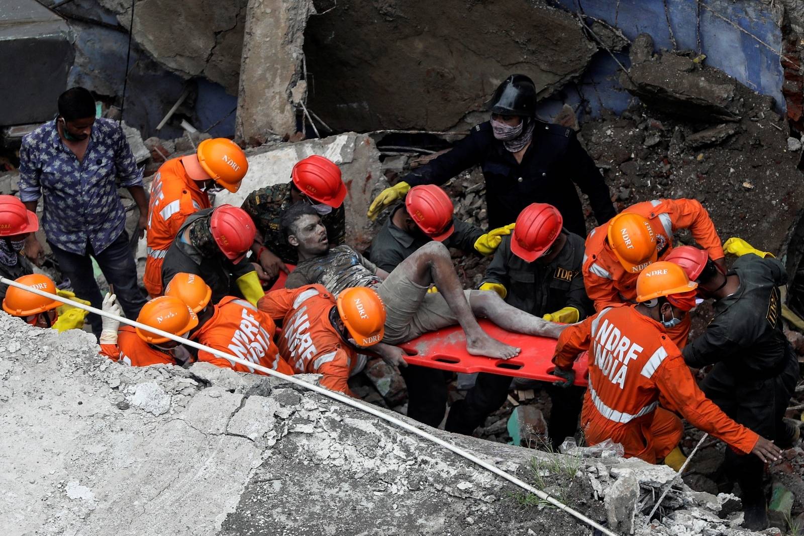 National Disaster Response Force (NDRF) officials rescue a man from the debris after a three-storey residential building collapsed in Bhiwandi on the outskirts of Mumbai, India