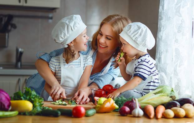 Healthy eating. Happy family mother and children prepares  vegetable salad