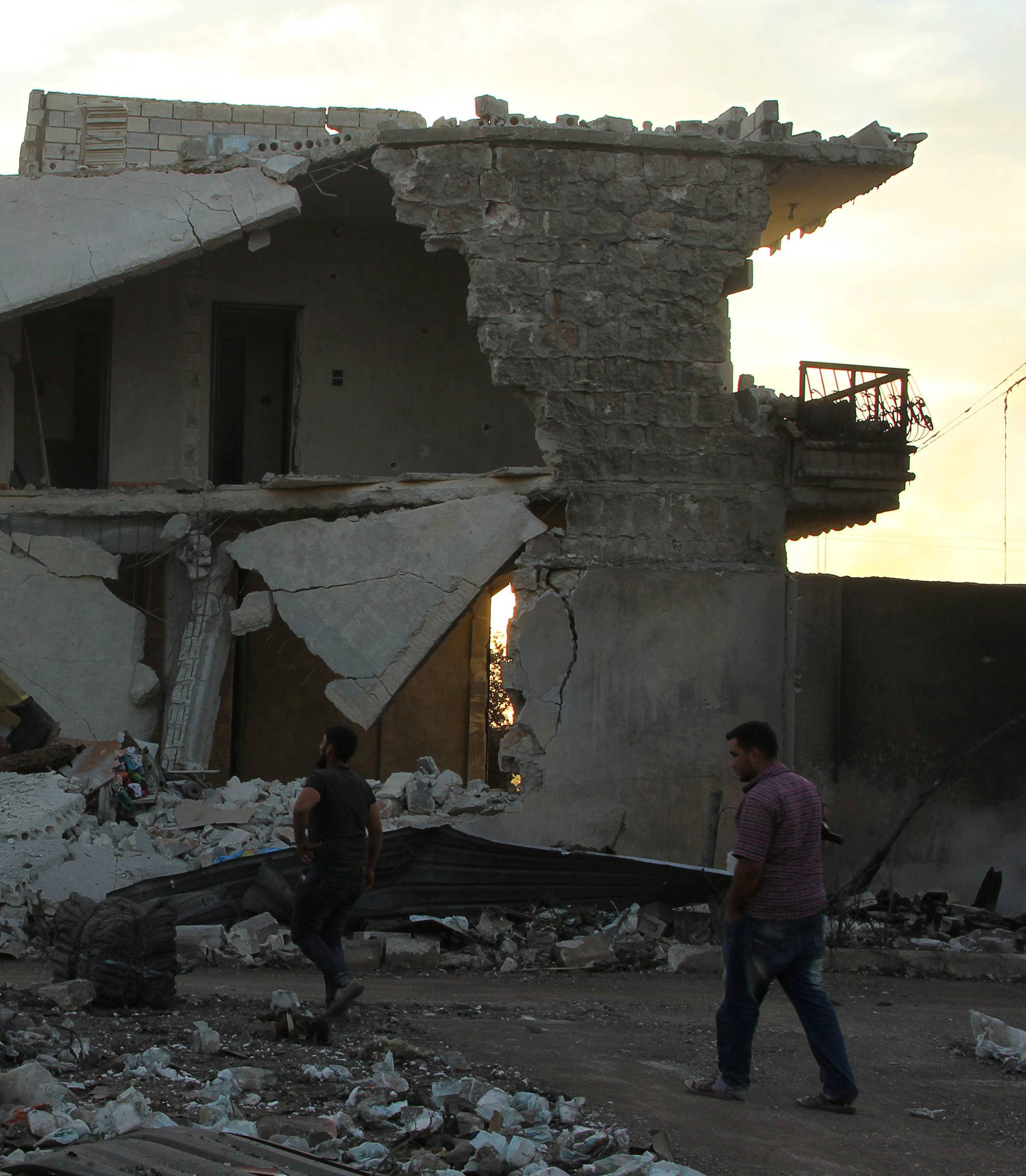 People inspect damage after an airstrike on the rebel held Urm al-Kubra town