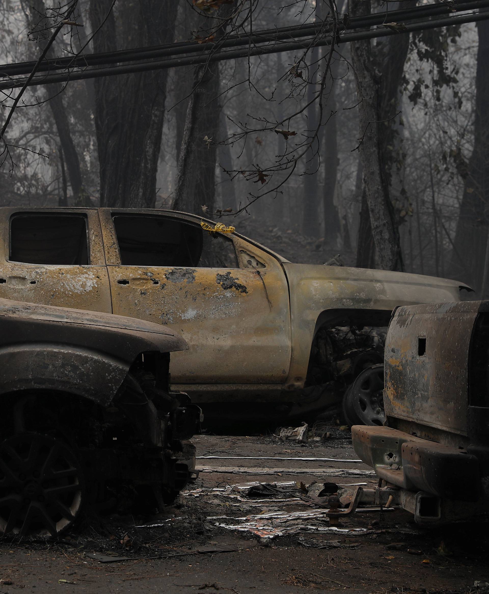 Yellow police tapes are seen on abandoned vehicles destroyed by the the Camp Fire in Paradise,