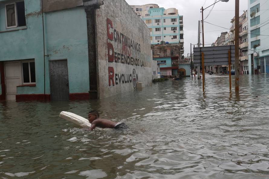 A boy floats with a foam board in a flooded street, after the passing of Hurricane Irma, in Havana