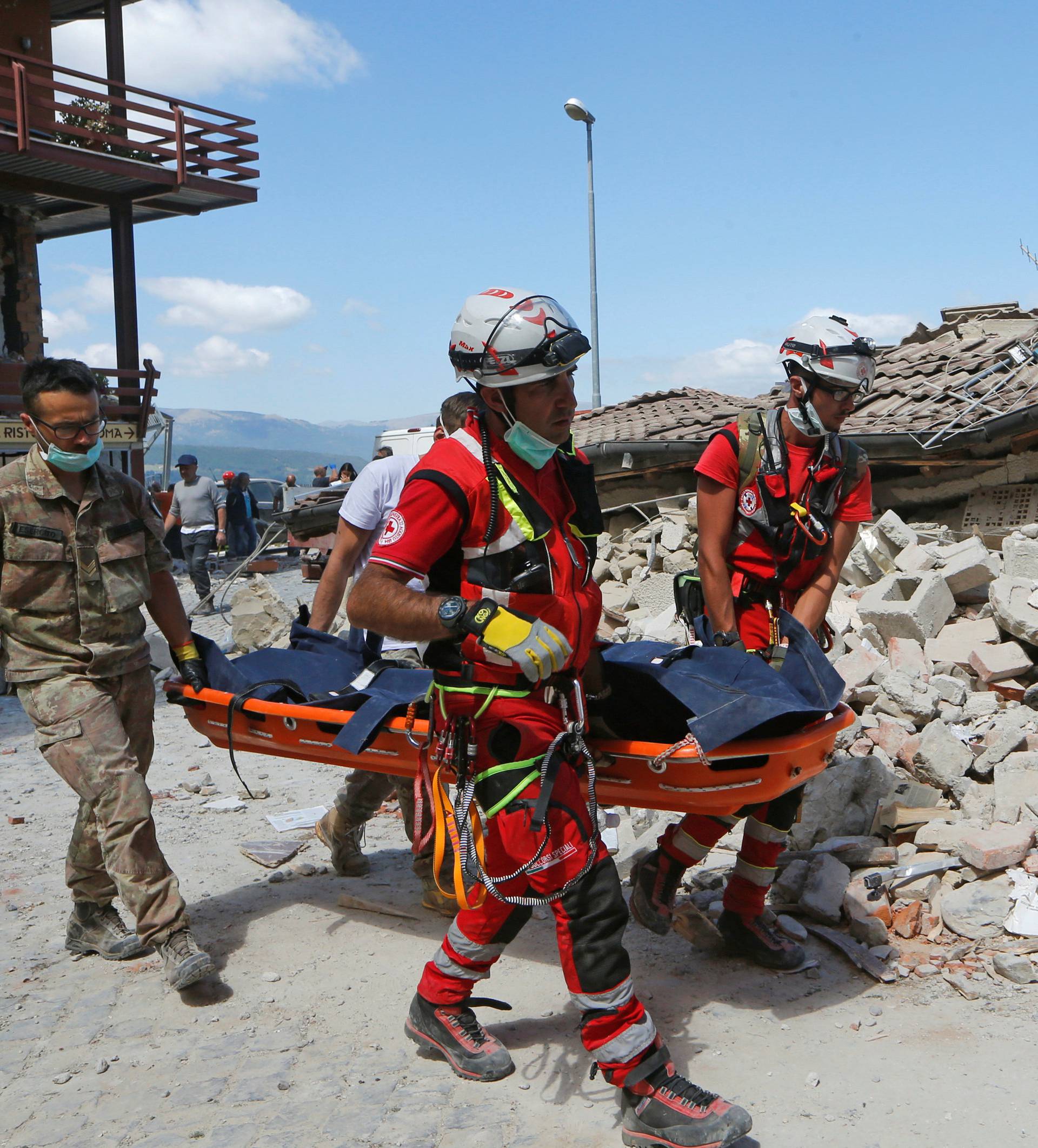 A body is carried away by rescuers following an earthquake in Amatrice