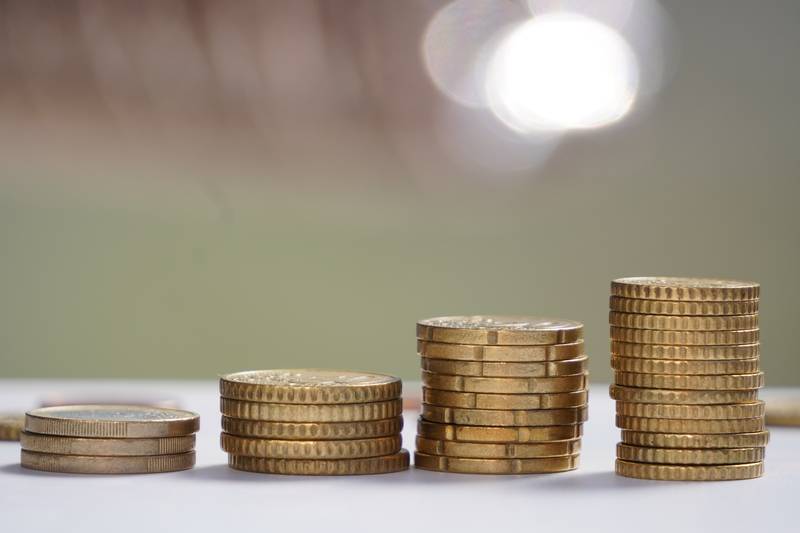 money to pay coins against blur multicolored background. Euro coins are stacked on top of each other in different positions. chart of currency rate rise or fall.