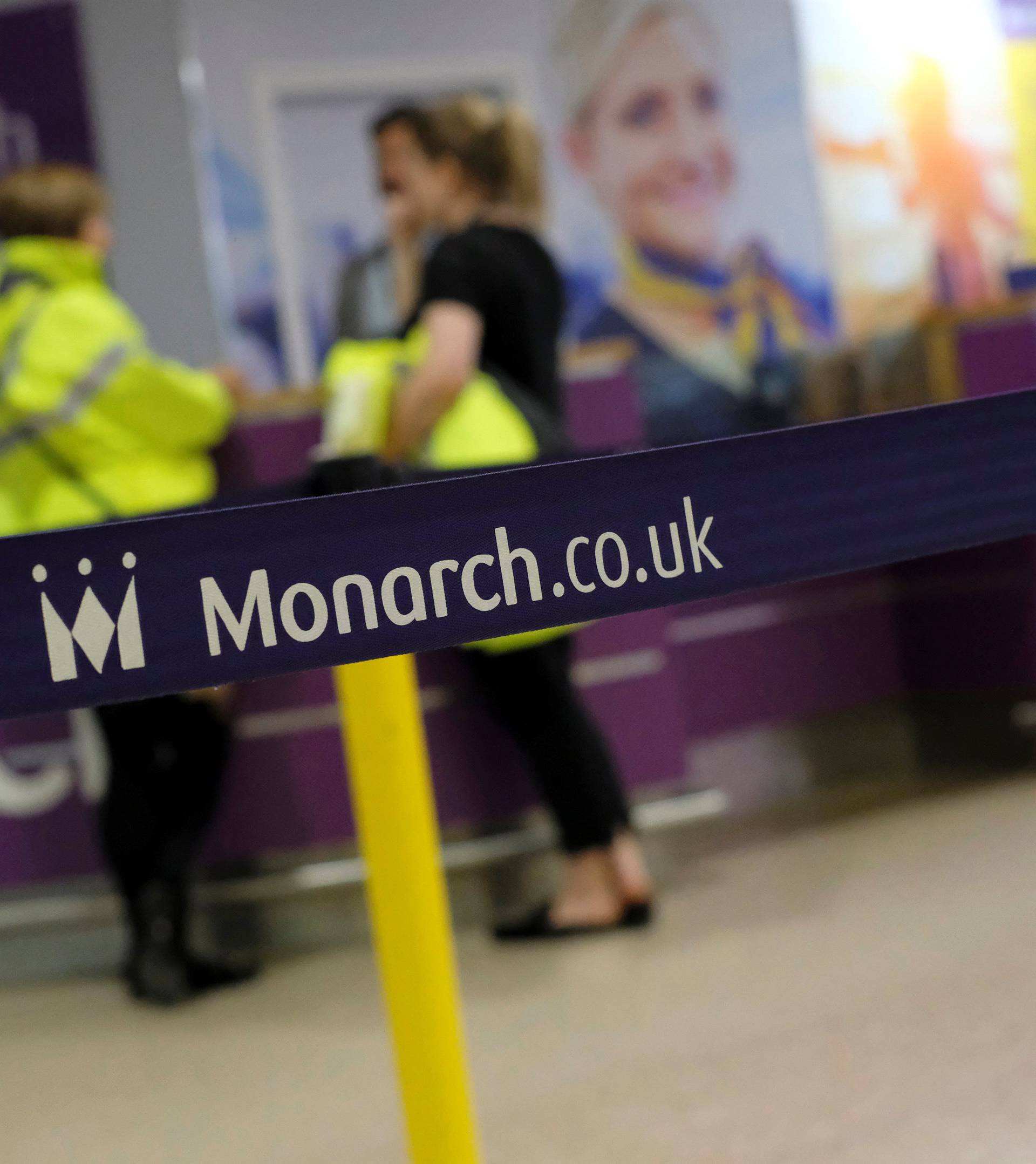 Airport staff speak by empty Monarch Airlines check-in desks after the airline ceased trading at Birmingham Airport