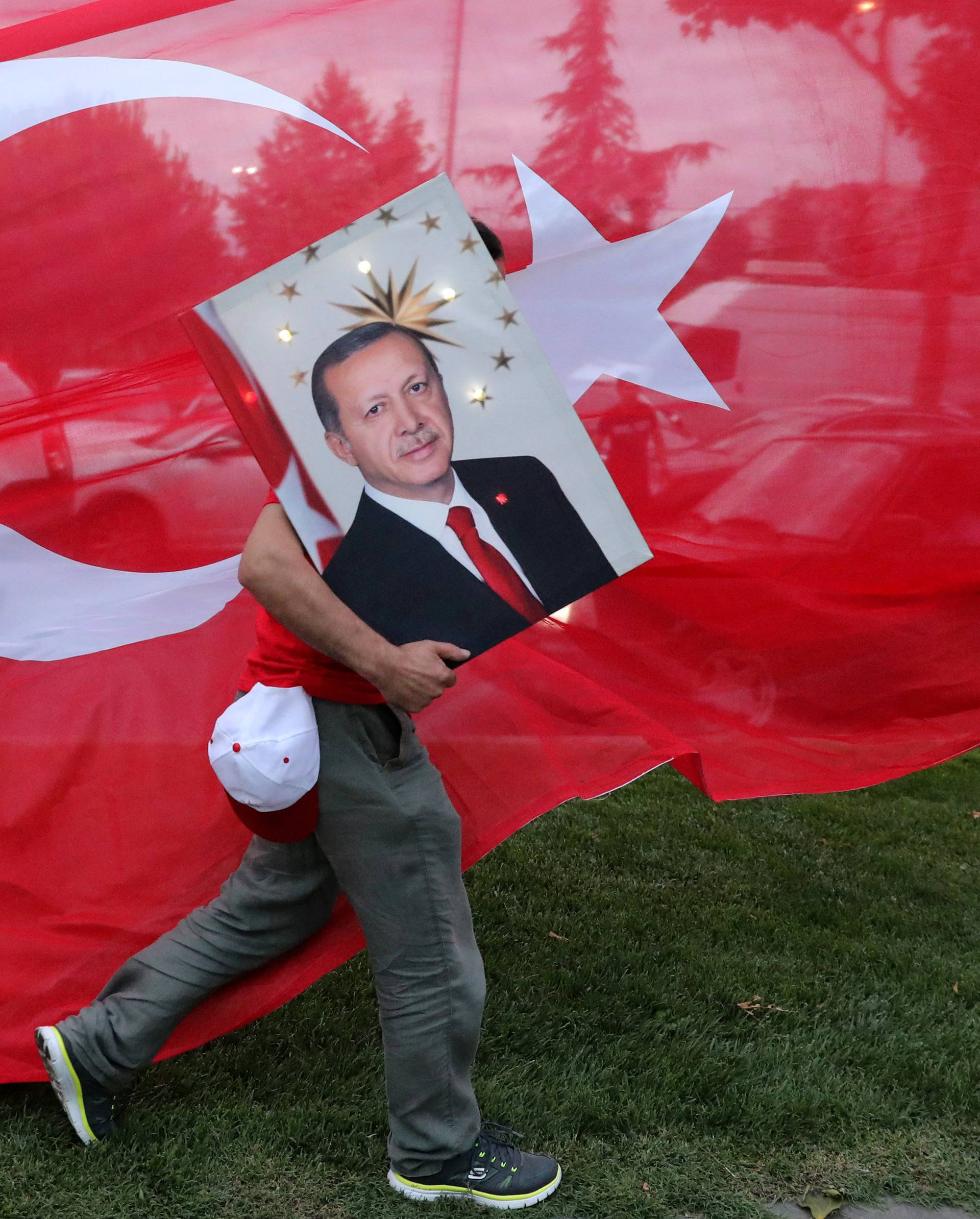 A supporters of Turkish President Tayyip Erdogan holds his picture in front of a Turkish flag, in front of Turkey's ruling AK Party (AKP) headquarters in Istanbul
