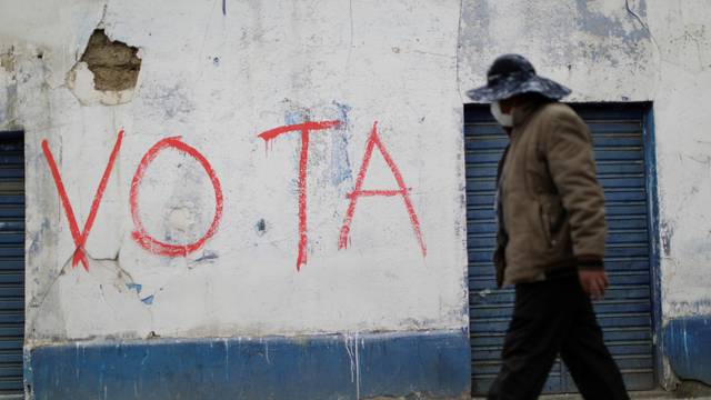 A man walks past a graffiti reading "Vote" in El Alto