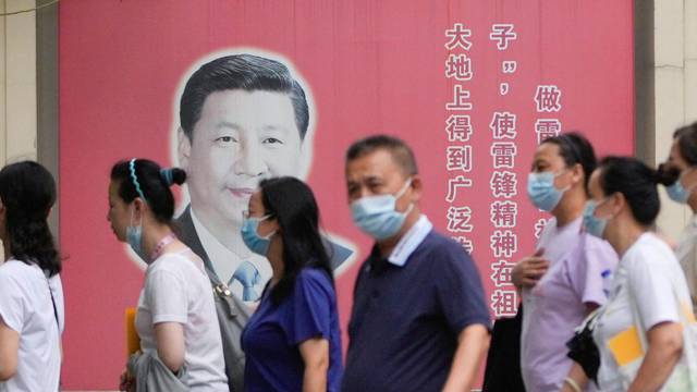 People wearing masks pass by portraits of Chinese President Xi Jinping and late Chinese chairman Mao Zedong, following the coronavirus disease (COVID-19) outbreak