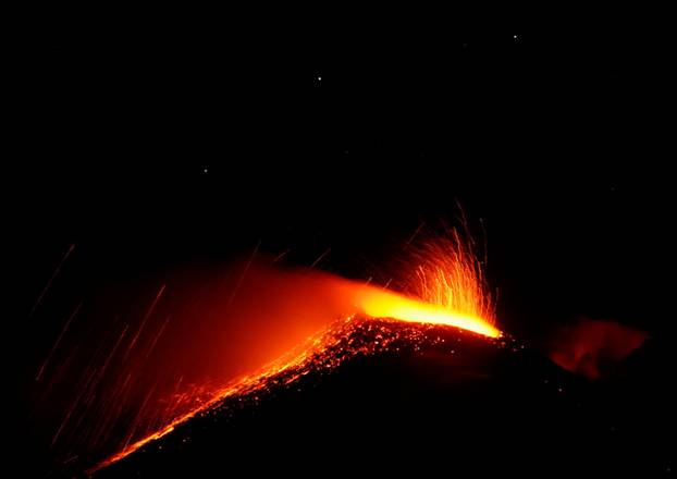 Large streams of red hot lava shoot into the night sky as Mount Etna, Europe