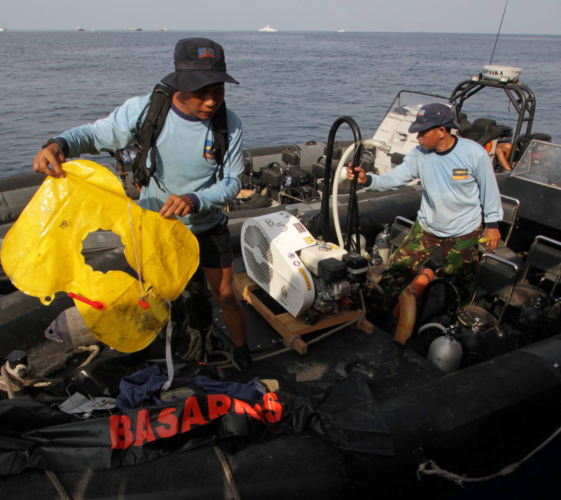 Indonesian Navy member holds a lifejacket recovered after the airplane's sea crash, off the coast of Karawang regency