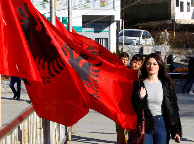 A girl passes next to Albanian flags ahead of tomorrow
