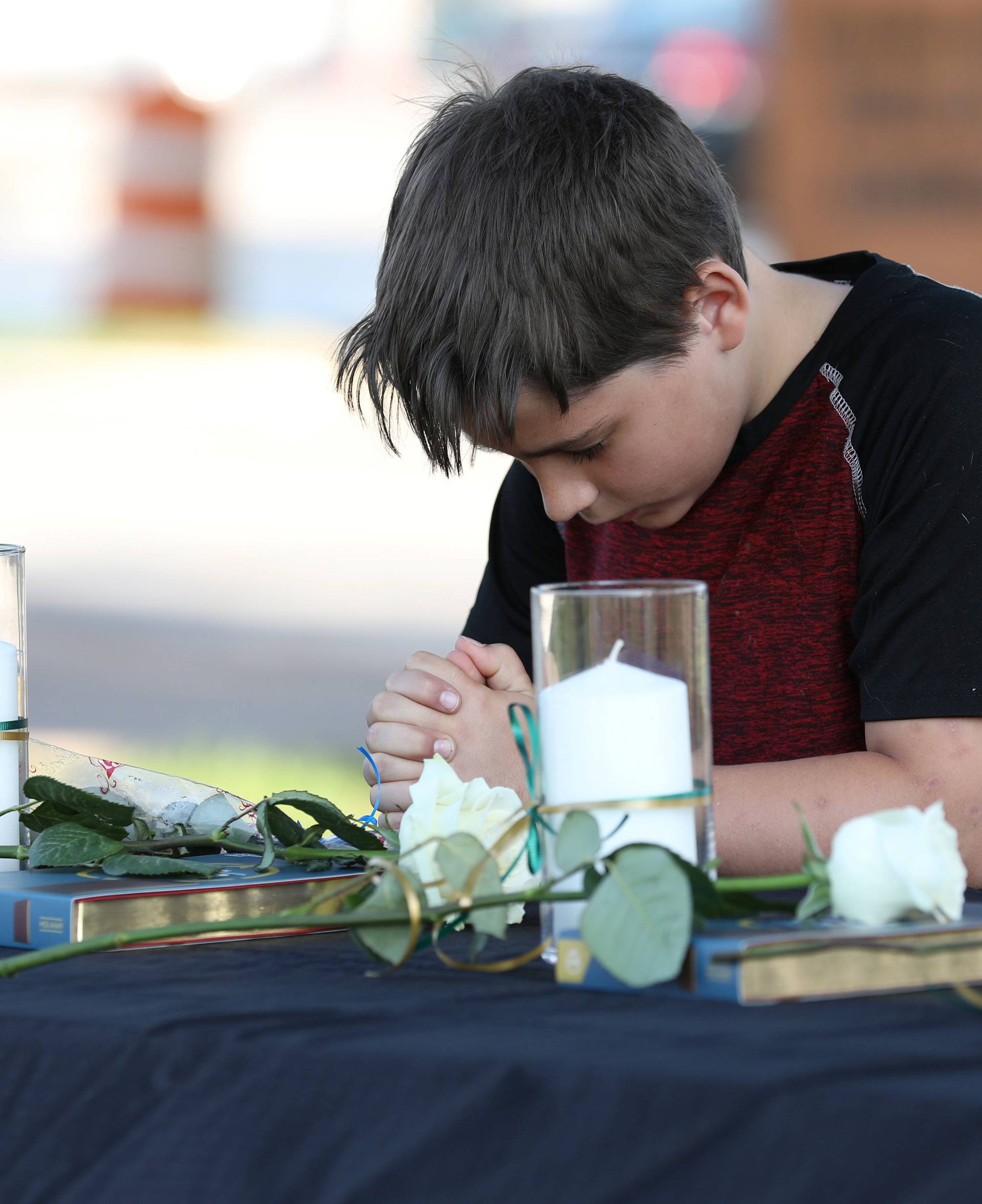 A young boy prays during a vigil held at the Texas First Bank after a shooting left several people dead at Santa Fe High School in Santa Fe, Texas