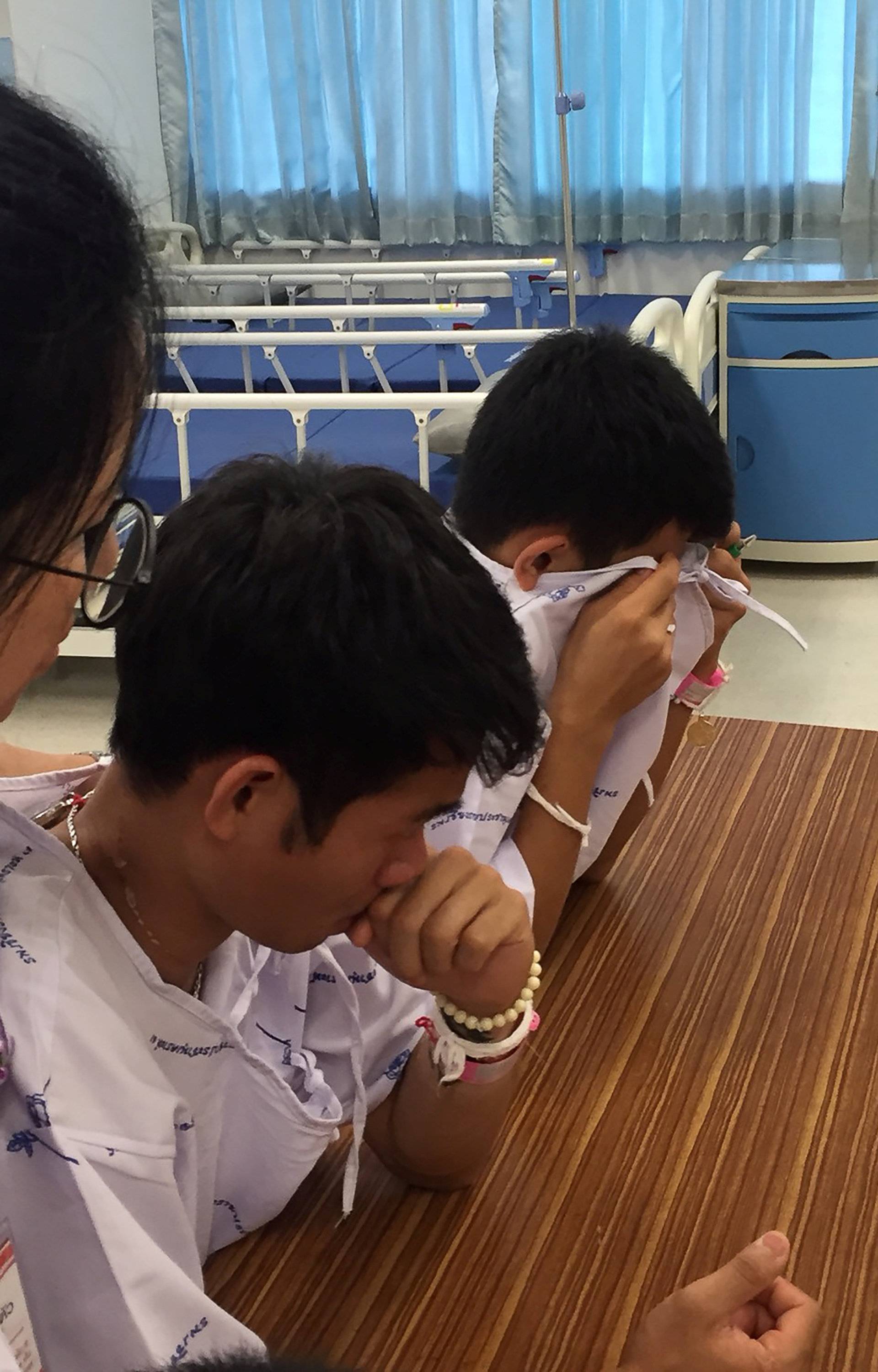 Members of the "Wild Boars" soccer team and their coach, rescued from a flooded cave, cry after writing messages on a drawing of Samarn Kunan, a former Thai navy diver who died working to rescue them, at the Chiang Rai Prachanukroh Hospital, in Chiang Rai