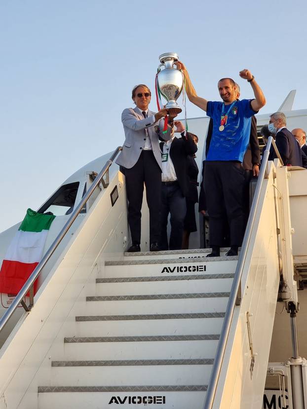 Italy coach Roberto Mancini and captain Giorgio Chiellini walk down steps of a plane holding the Euro 2020 cup at Fiumicino airport near Rome