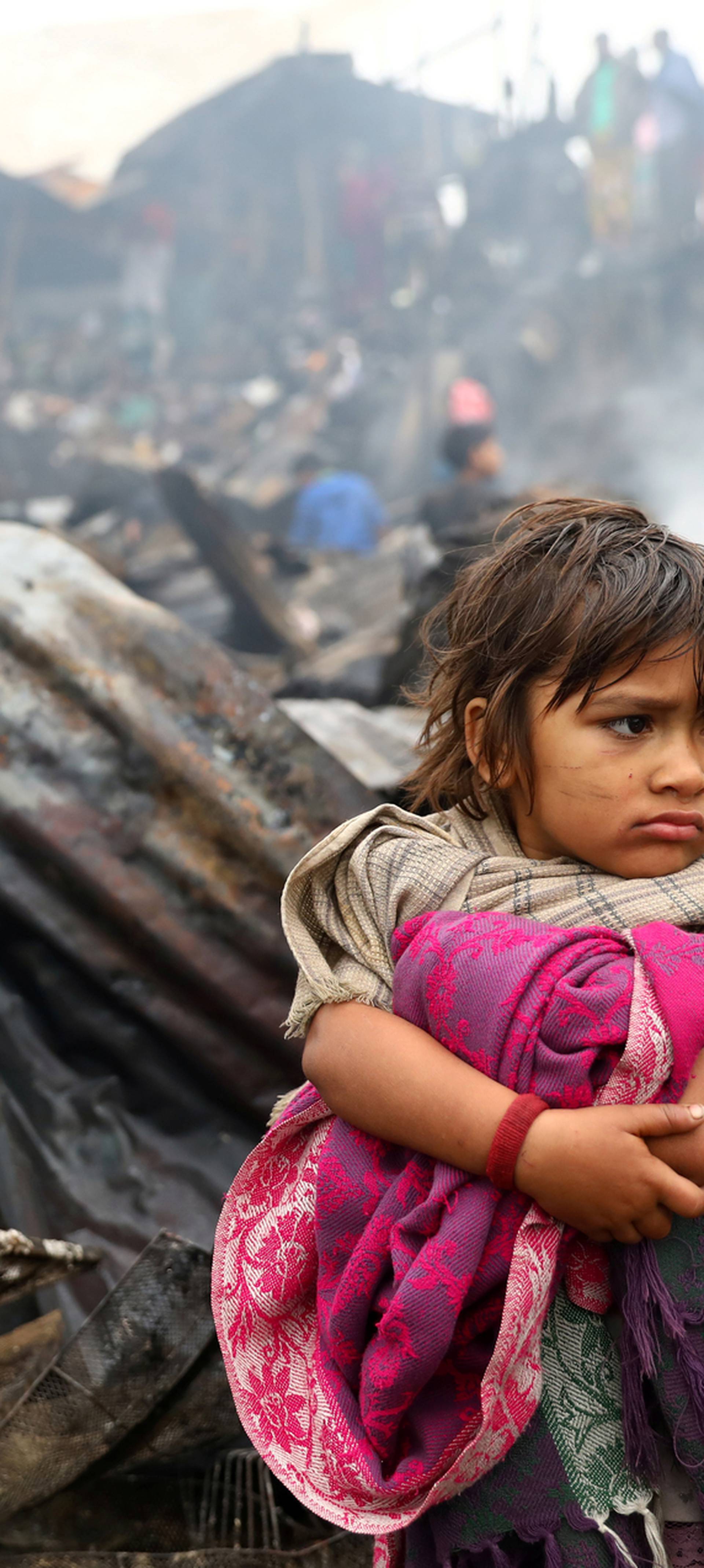 Child looks on, whose shelter has been burned after a fire broke out in a slum in Dhaka