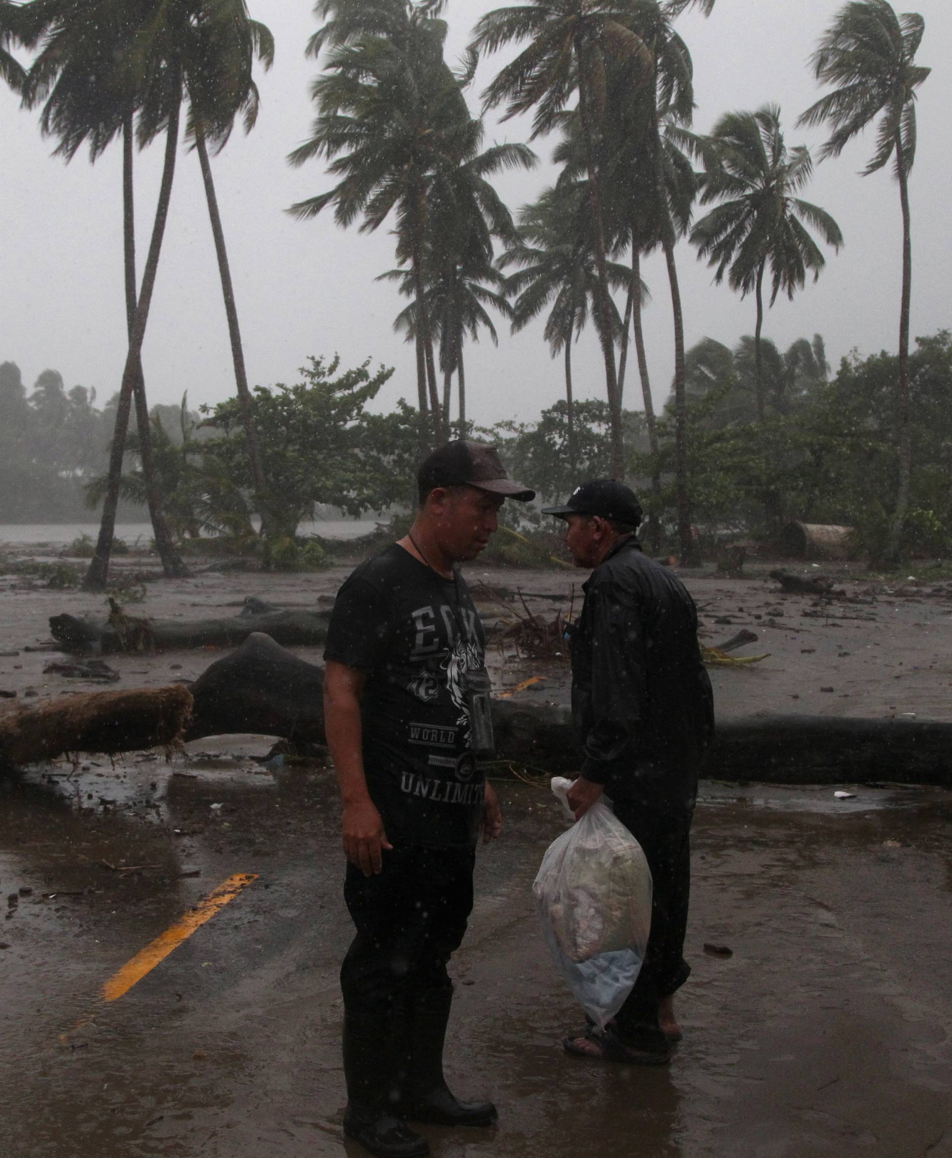 Men stand in the rain as Hurricane Irma moves off from the northern coast of the Dominican Republic, in Nagua