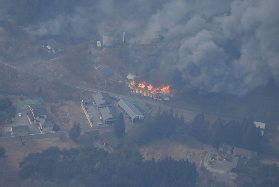An aerial views shows a building on fire due to the spread of a wildfire in Ofunato, Japan