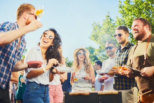 Small,Group,Of,People,Standing,Around,Barbecue,Grill,At,Outdoor