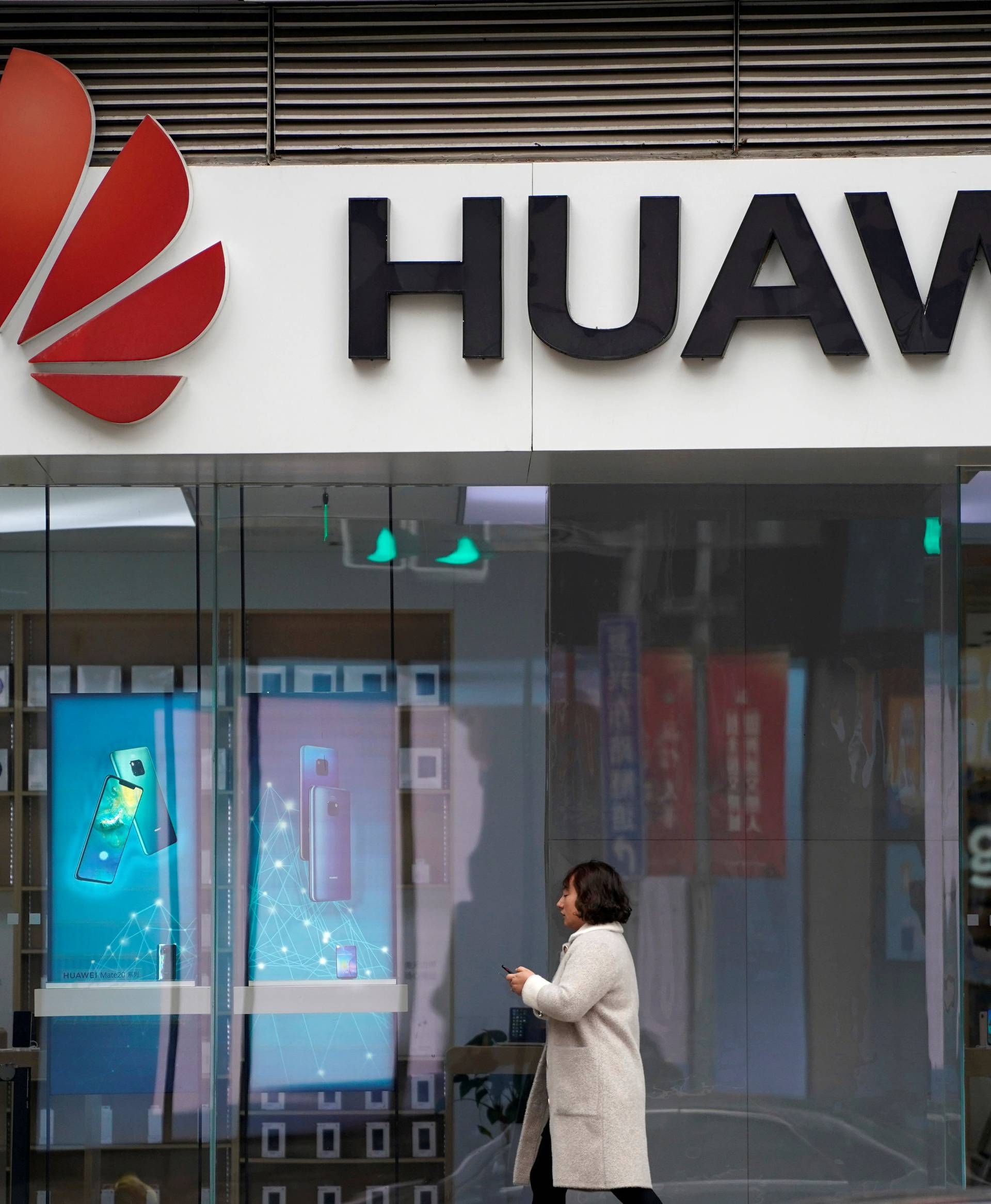 FILE PHOTO: A woman walks by a Huawei logo at a shopping mall in Shanghai