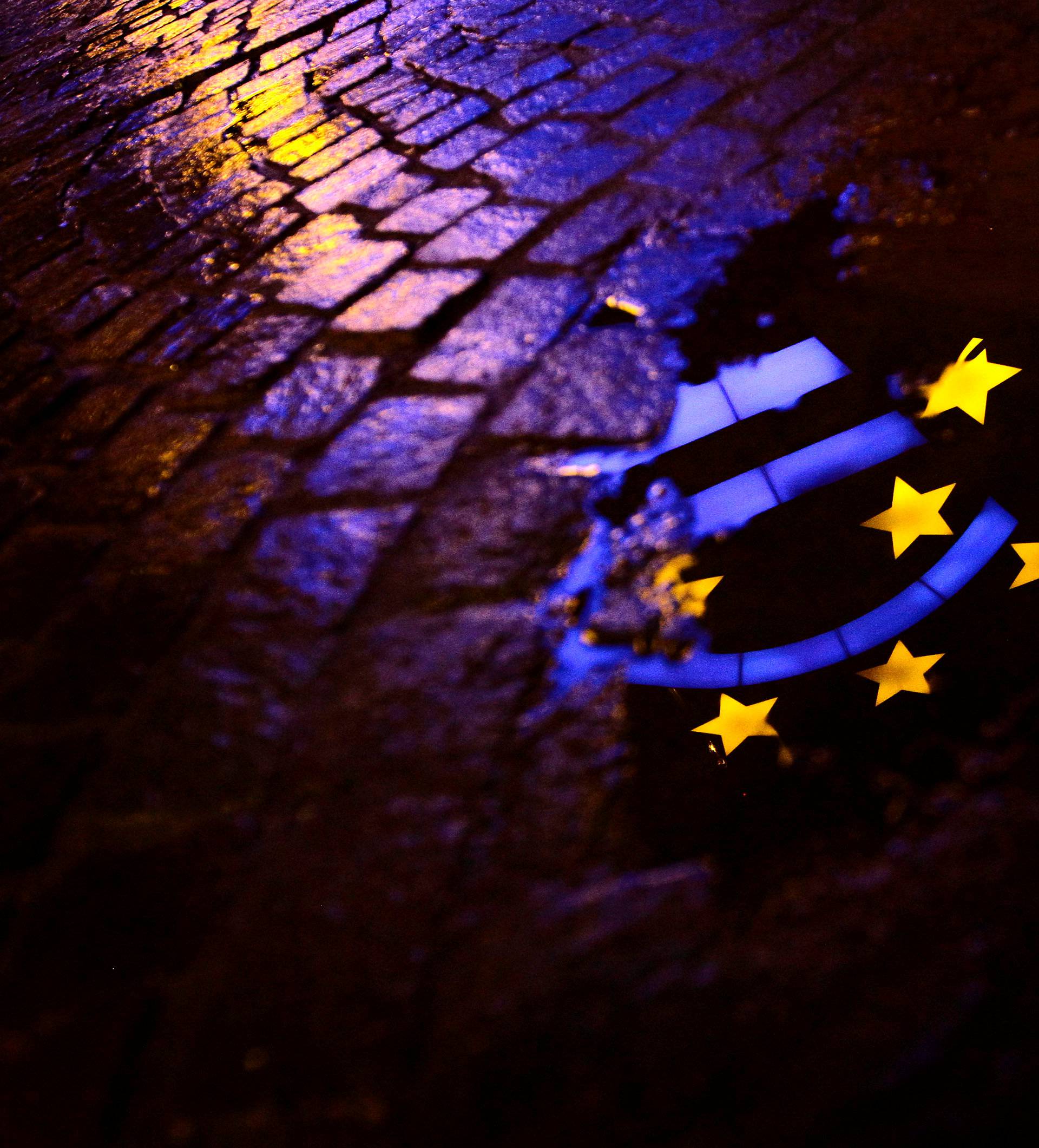 Euro sculpture is partially reflected in a puddle in front of the headquarters of the ECB headquarters in Frankfurt