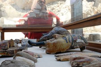A woman stands near artefacts from the recently discovered tomb of Amenemhat, a goldsmith from the New Kingdom on display at the Draa Abu-el Naga necropolis near the Nile city of Luxor, south of Cairo