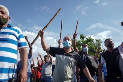 Plain clothes police and government supporters react during protests against and in support of the government, in Havana