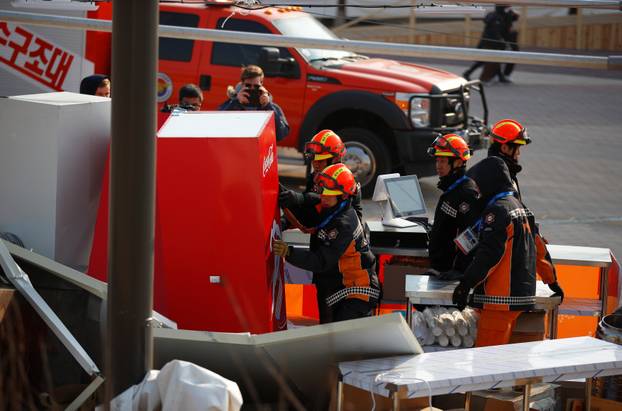 Firefighters remove a fridge in a food stall that was blown over by the wind