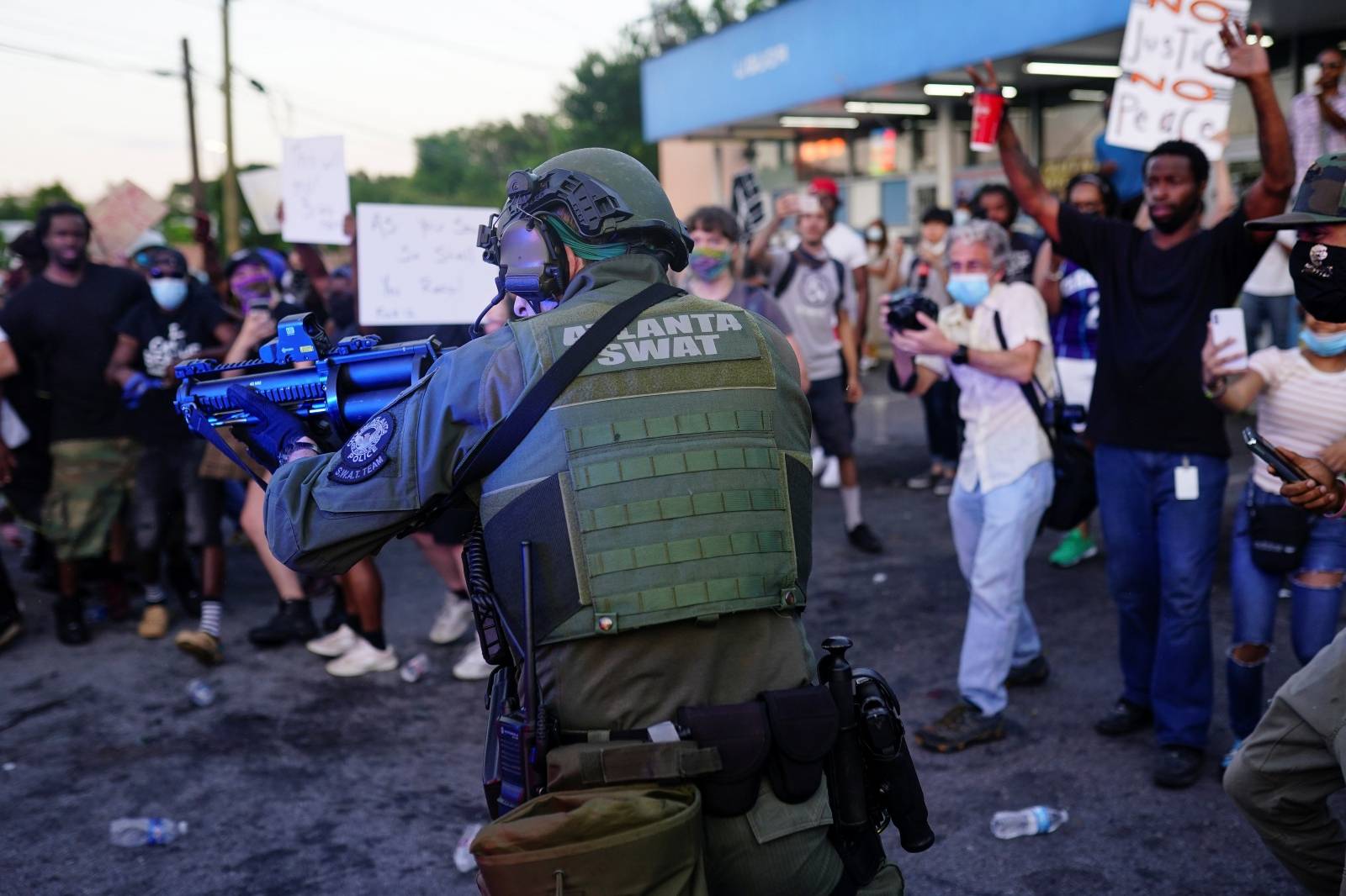 An Atlanta SWAT officer draws his weapon during a rally against racial inequality and the police shooting death of Rayshard Brooks, in Atlanta