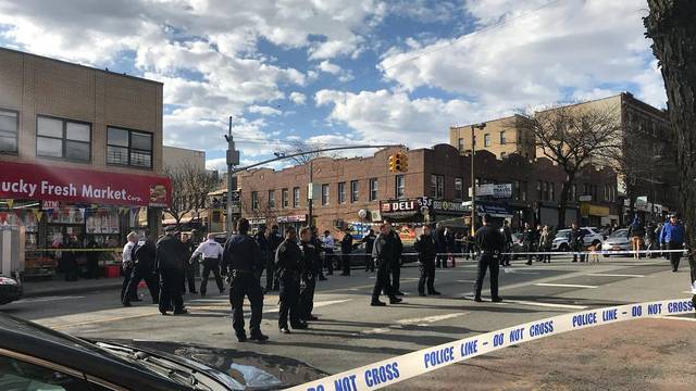 Police officers stand behind a cordon tape at the scene of a shooting in Brooklyn, New York