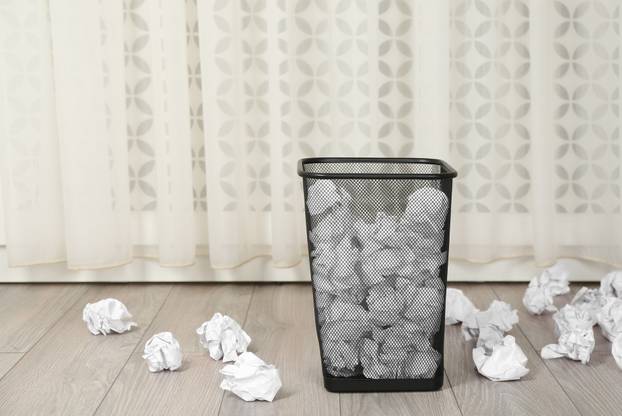 Basket with crumpled paper on floor indoors. Space for text