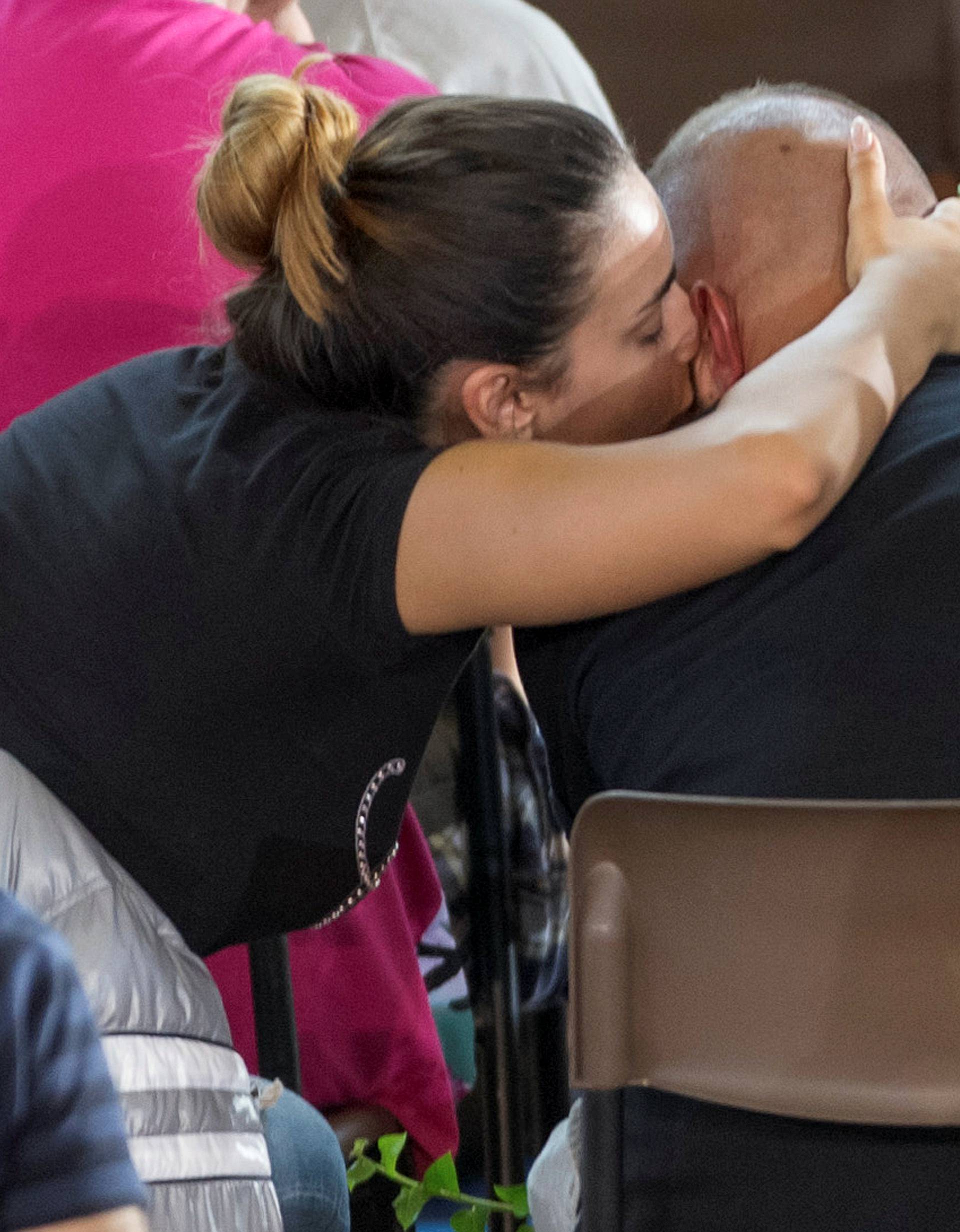 A woman kisses and hugs a man during the funeral service for victims of the earthquake inside a gym in Ascoli Piceno