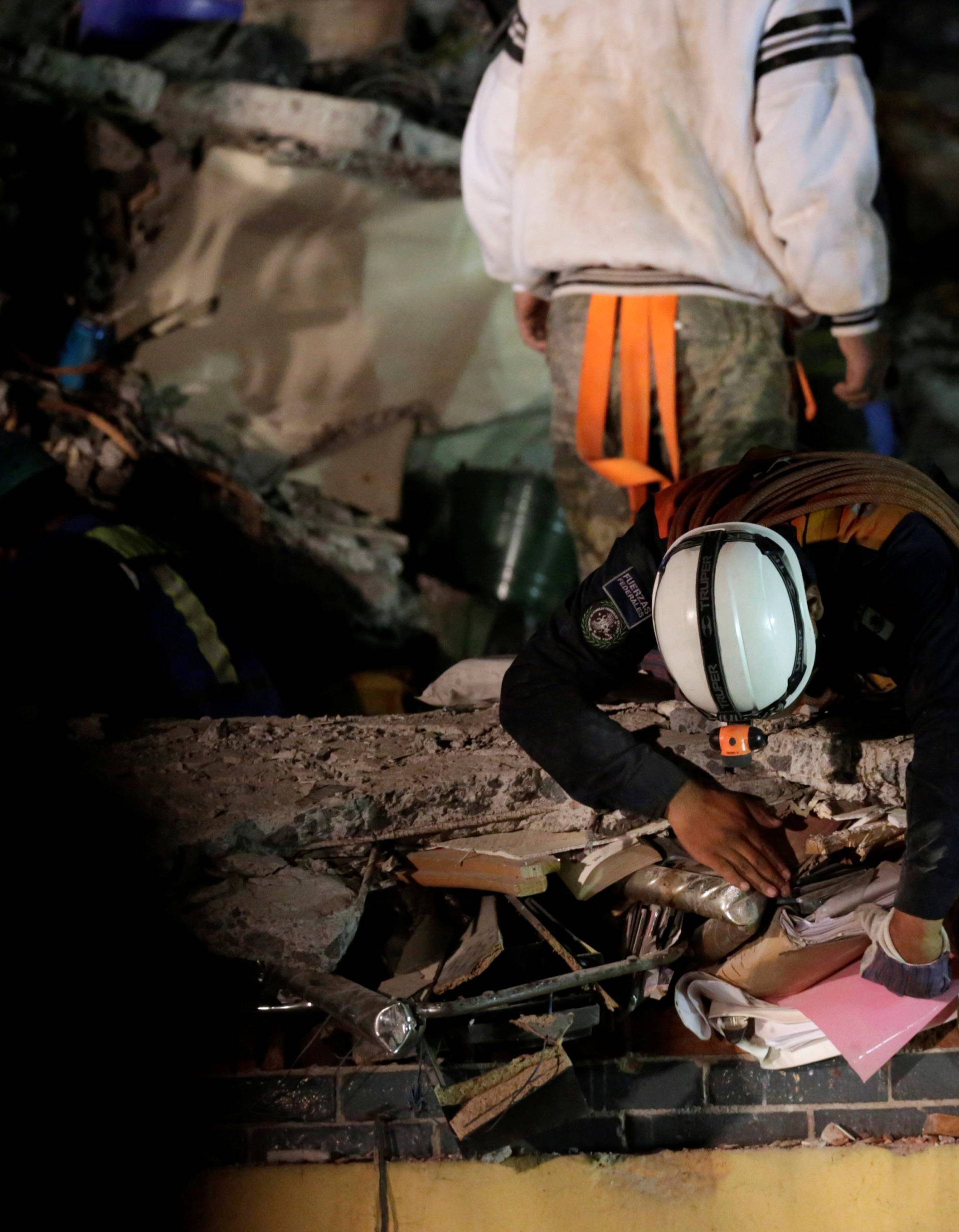 A rescue worker pulls binders from the rubble of a collapsed multi family residential after an earthquake in Mexico City