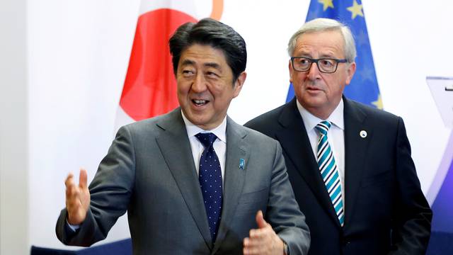Japan's Prime Minister Shinzo Abe gestures beside European Commission President Jean-Claude Juncker before a working dinner at the EU Council in Brussels