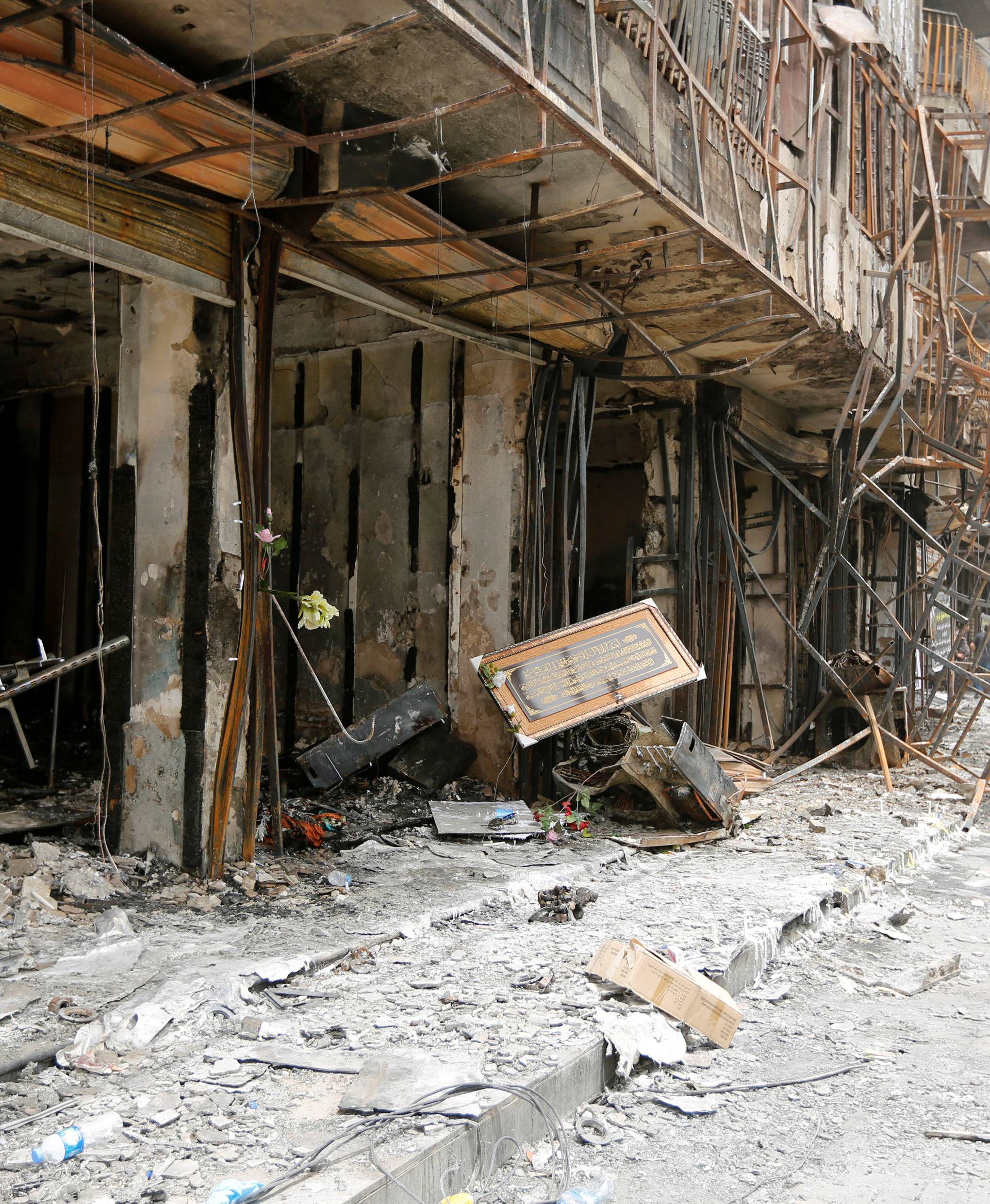 A girl walks past the site after a suicide car bomb attack at the shopping area of Karrada, a largely Shi'ite district, in Baghdad