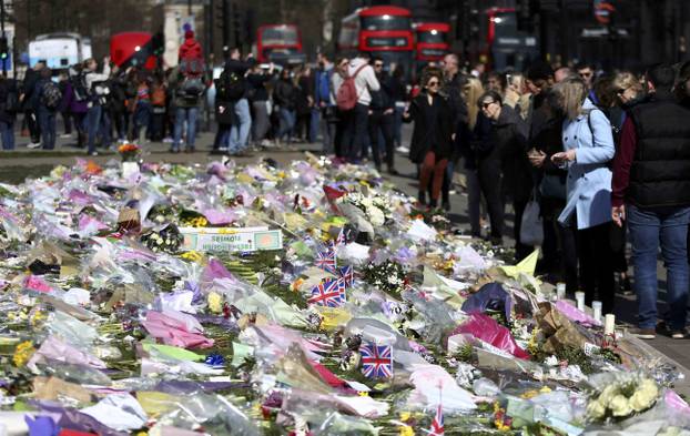 Onlookers view floral tributes laid in Parliament Square following the attack in Westminster earlier in the week