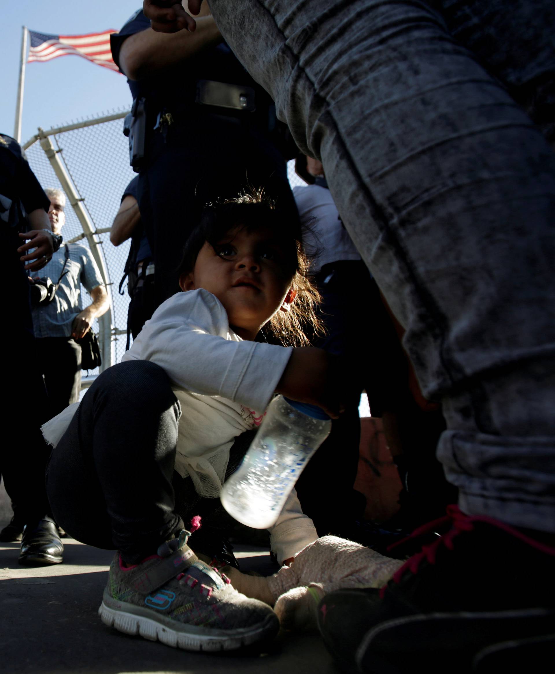 Migrant families from Mexico listen to officers of the U.S. Customs and Border Protection before entering the United States to apply for asylum at Paso del Norte international border crossing bridge in Ciudad Juarez