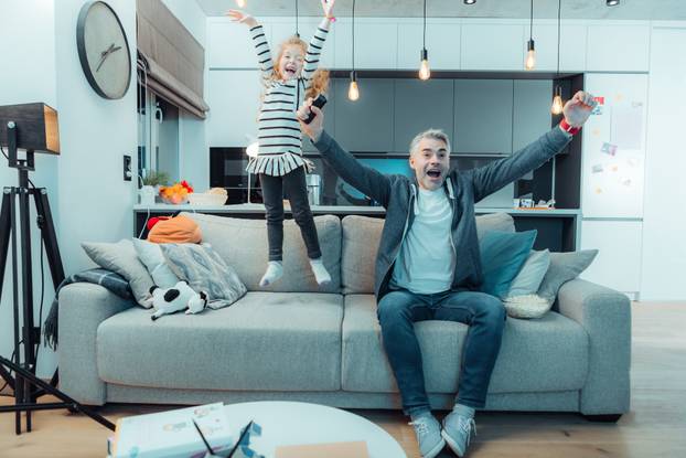 Pretty long-haired girl in a dress and her grey-haired father feeling happy