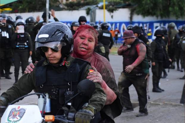 Police rescue Vinto mayor Patricia Arce Guzman on a motorcycle after people threw paint and dirt on her following a fire in Vinto