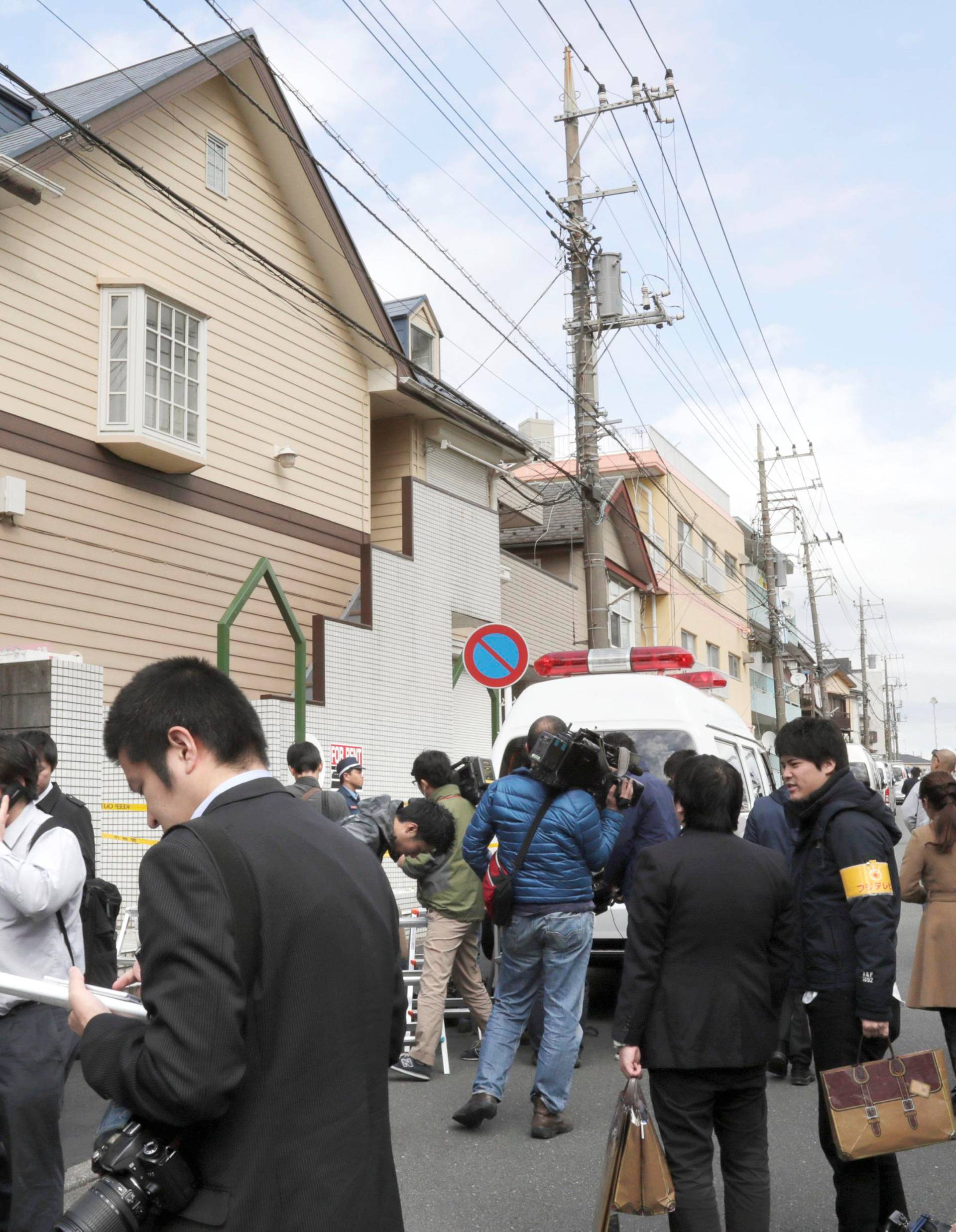 Members of the media gather in front of an apartment building where media reported nine bodies were found in Zama