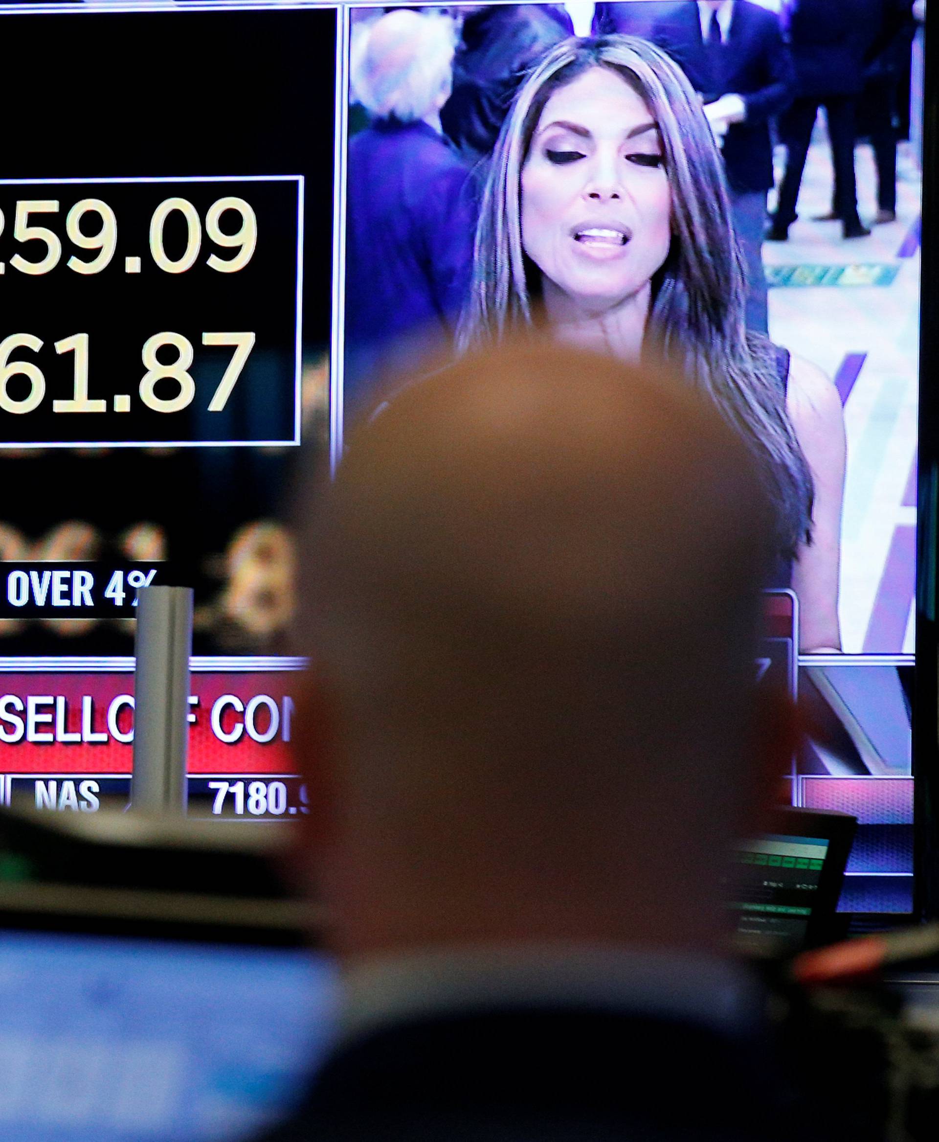 A trader looks at a screen that displays the Dow Jones Industrial Average on the floor of the NYSE in New York