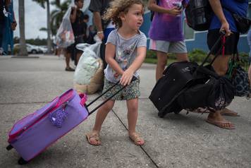 A girl carries her belongings into a shelter ahead of the downfall of Hurricane Irma in Estero, Florida