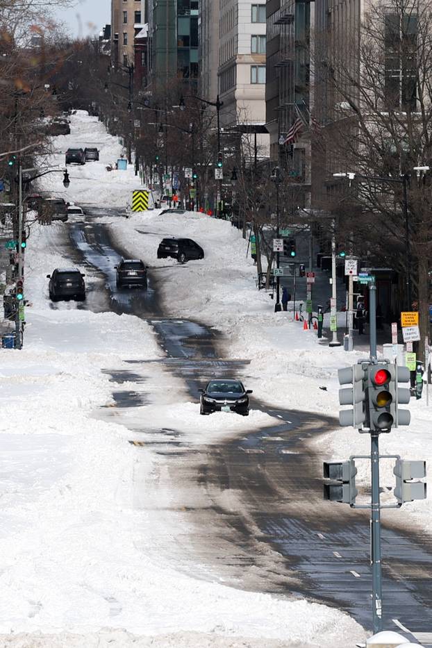 A car is stuck in the middle of 12th Street NW as other cars navigate the street after a winter storm in Washington
